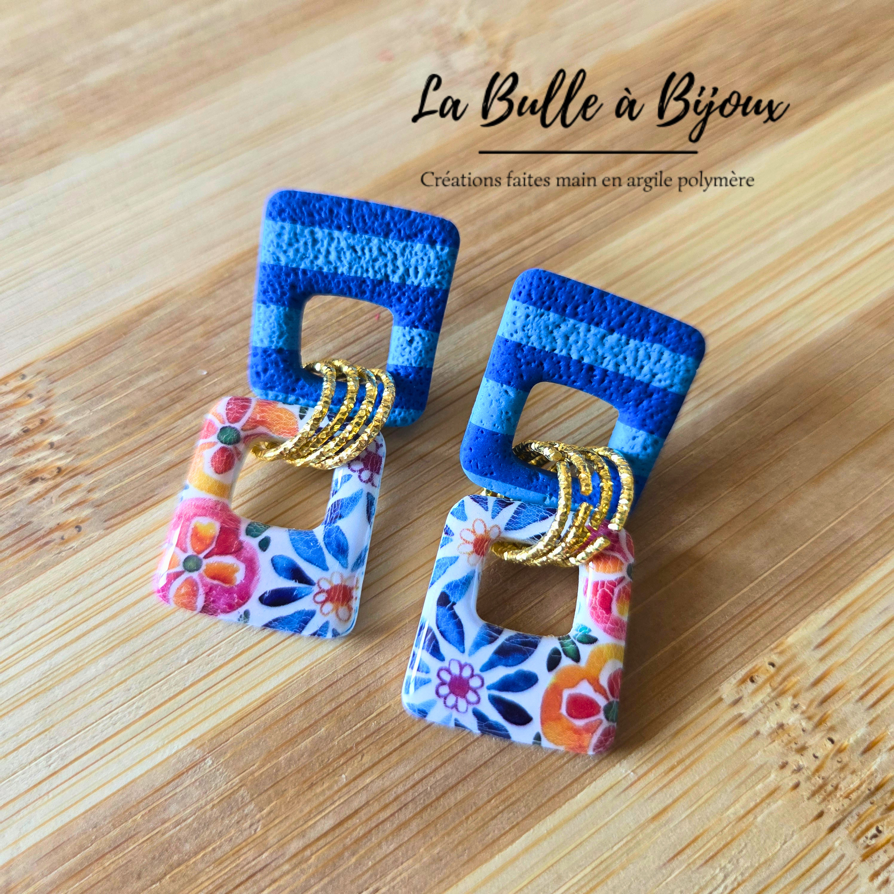 deux trapèzes évidés inversés rayures bleu royal bleu clair en haut imprimé carreaux ciment en bas reliés par 3 anneaux de jonction acier inoxydable effet martelé couleur or