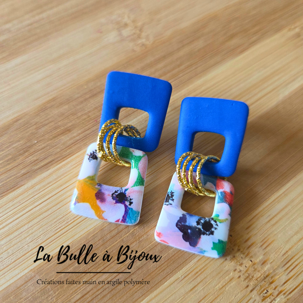 deux trapèzes évidés inversés couleur pleine bleu royal en haut imprimé fleuri en bas reliés par 3 anneaux de jonction acier inoxydable effet martelé couleur or